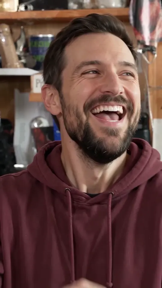The same bearded man laughs with his mouth wide open and looks up, grinning